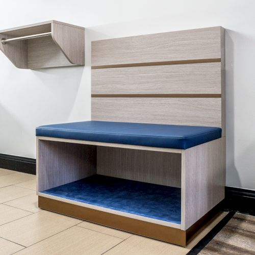 The image shows a modern bench seat with blue cushioning and a matching shelf above it attached to the wall, placed in a room with tiled flooring.